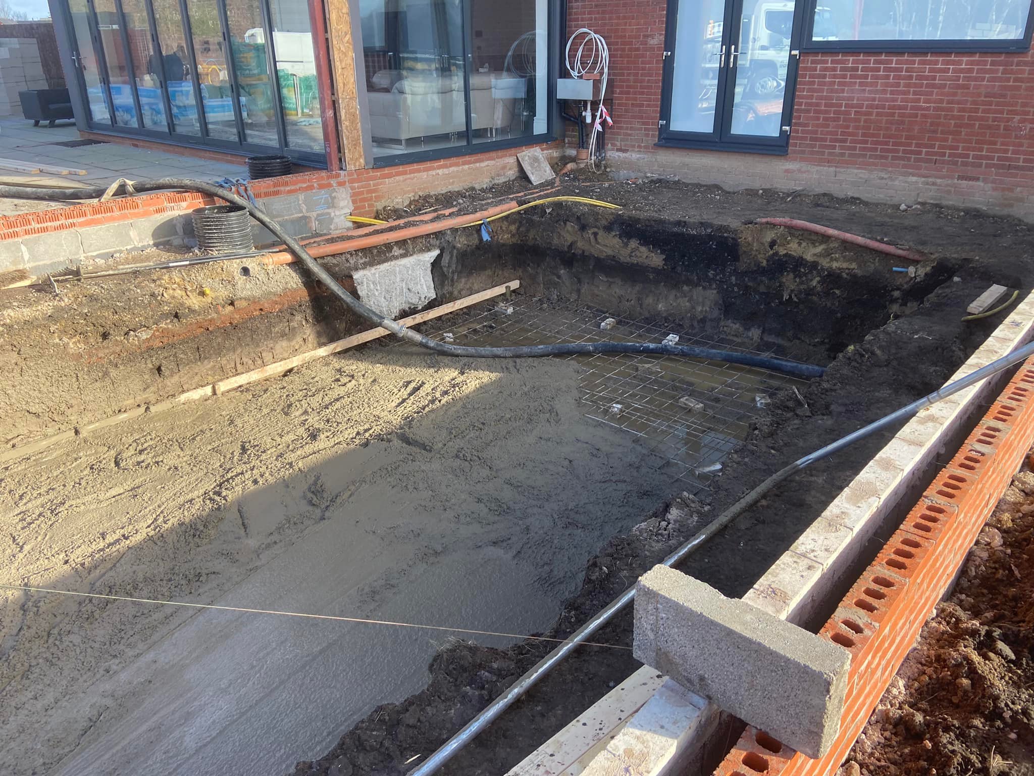 Concrete being poured over reinforcing mesh for a foundation slab