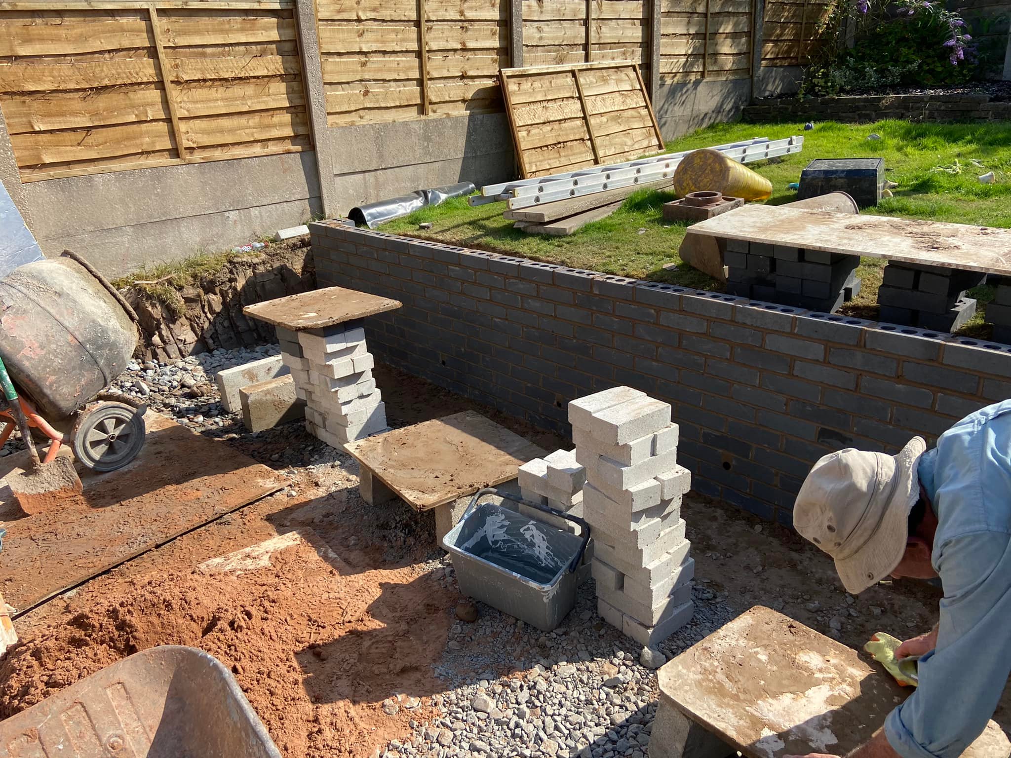 Garden groundwork and concrete block wall construction beside a lawn